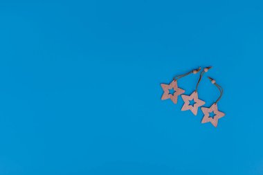 Yeni yıl ve Noel oyuncakları mavi arka planda. Lazer, tahta yıldız heykelciklerini kesti. Metin için boş alanı olan bir kartpostal kompozisyonu. Yeni yıl ve Noel konsepti. Kopyalama alanı olan düz. 