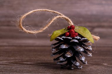 Çam kozalaklarından yapılmış el yapımı Noel ağacı oyuncakları, kesilen ağacın arka planına karşı doğal malzemelerle süslenmiş. Kenevir sicimin süspansiyonuyla süslenmiş. Yeni yıl ve Noel konsepti.