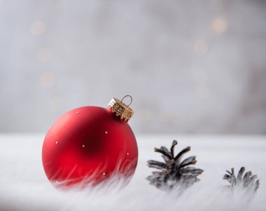 Kırmızı bir Noel topu ve açık tahta bir masanın üzerindeki koniler ve kürk yakın plan. Boşluğu kopyala