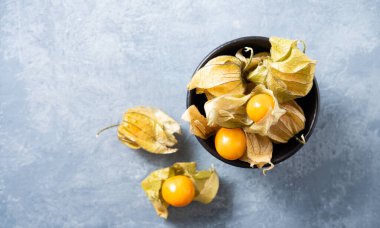 Mavi arka planda kabuklu taze sarı peruvana physalis. Üst görünüm ve boşluk kopyala. Dikey resim