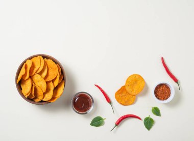  Kırmızı biberli Meksika cipsi, baharat ve sarı arka planda barbekü sosu. Üst görünüm ve kopyalama alanı