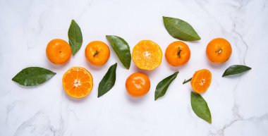 Düz, beyaz mermer zemin üzerinde tatlı mandalinalar ve yeşil yapraklar yatıyordu. Üst görünüm ve yatay yönelim