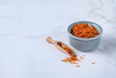 Mermer bir masanın üzerinde mavi bir seramik kasede oryantal baharat safranı. Boşluğu kopyala