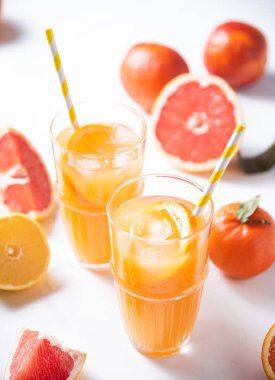 İki bardak portakal suyu ve beyaz arka planda taze meyve mandalinası, portakal, greyfurt ve limon. Üst görünüm