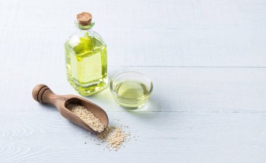 Tahta arka plandaki berrak bir şişede susam tohumlarından elde edilen doğal sebze yağı. Sağlıklı beslenme. Üst görünüm ve kopyalama alanı