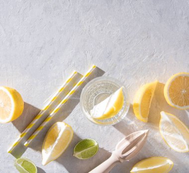 sulu limon ve limon dilimleri ve sert sabah gölgeleri olan beyaz bir masada limonlu bir bardak maden suyu. Üst görünüm ve kopyalama alanı