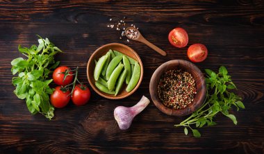 Sağlıklı yiyecekler. Taze aromatik fesleğen, sarımsak, domates ve ahşap zemin üzerinde ahşap tabakta baharatlı biber. Üst görünüm ve düz uzanma.