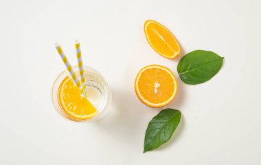 Bir bardak maden suyu ve portakal dilimi taze meyve portakalları ve yeşil yapraklarla dolu bir masada. Yaz zamanı. En üst görüntü