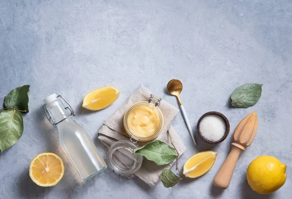 早餐平铺概念 美味的自制柠檬凝乳在一个玻璃瓶中与柠檬片 糖和果汁瓶蓝色背景 顶视图和复制空间图像 — 图库照片
