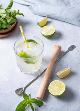 Masada limon dilimleri, meyve sıkacağı, kaşık ve naneli limonata mojito var. En üst görüntü