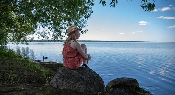 Little Girl Orange Dress Hat Sitting Stone Shore Lake Looking — Stock Photo, Image