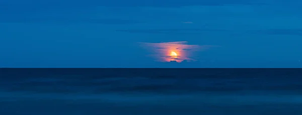 Beautiful view of the moon in the clouds over the surface of Lake Ladoga. Long exposure and copy space image
