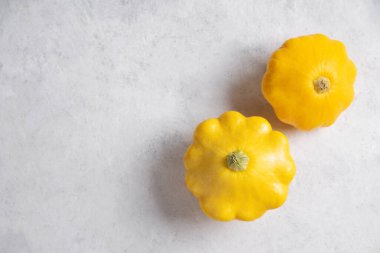 Açık dokulu arka planda iki sarı çalılık balkabağı. Üst görünüm ve boşluk resmi kopyala