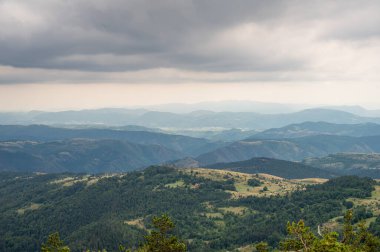Doğal arka planda, kasvetli bulutlu gökyüzü altında yeşil ormanlı dağlar ve vadilerin geniş bir manzarası var. Vahşi yaşam ve seyahat konsepti. Zlatibor, Sırbistan