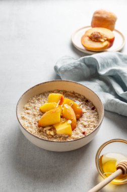 Şeftalili ve fındıklı yulaf ezmesi. Arka planda bal, peçete ve taze meyve var. Sağlıklı bir vejetaryen yemeği ya da atıştırmalık bir şeyler. Üst görünüm, alanı kopyala.