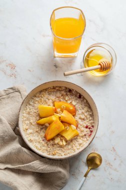 Ballı, şeftalili ve fındıklı yulaf ezmesi. Bir bardak portakal suyu, kaşık ve peçete. Sağlıklı bir vejetaryen yemeği ya da atıştırmalık bir şeyler. Üst görünüm, alanı kopyala.