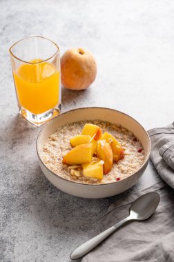 Şeftalili ve fındıklı yulaf ezmesi. Arka planda bal, bir bardak portakal suyu, kaşık ve çırılçıplak. Sağlıklı bir vejetaryen yemeği ya da atıştırmalık bir şeyler. Üst görünüm, alanı kopyala.