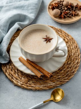 Geleneksel Hint masala çayı sütlü ve baharatlı açık mavi arka planda, kaşık ve peçeteli. Menü için sıcak içecek konsepti ya da etnik kafe ya da restoran afişi. Üst görünüm.