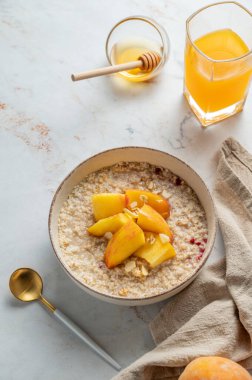 Ballı, şeftalili ve fındıklı yulaf ezmesi. Bir bardak portakal suyu, kaşık ve peçete. Sağlıklı bir vejetaryen yemeği ya da atıştırmalık bir şeyler. Üst görünüm, alanı kopyala.