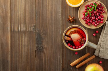 Tarçınlı, böğürtlenli ve meyveli koyu ahşap bir fincanda sıcak bir şarap. Geleneksel sıcak punç ya da portakal, elma ve baharatlı Noel içeceği. Üst görünüm, alanı kopyala.