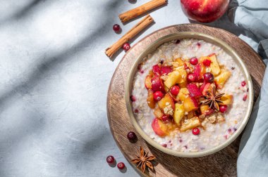 Bir gecede elma, kızılcık ve tarçınlı yulaf ezmesi ahşap bir tahtanın üzerinde mavi bir zeminde, böğürtlen ve sabah gölgeleriyle. Kahvaltıda sağlıklı bir vejetaryen yemeği. Reklam menüsü ya da afiş kafe. Üst görünüm, alanı kopyala.