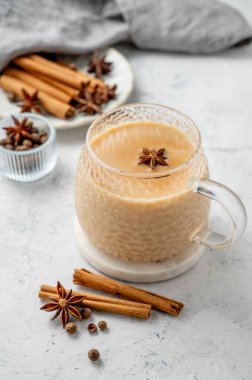 Tarçın, anason ve peçeteli hafif bir arka planda sütlü ve baharatlı geleneksel Hint masala çayı. Etnik kafe veya restoran için sıcak içecek konsepti veya pankart.
