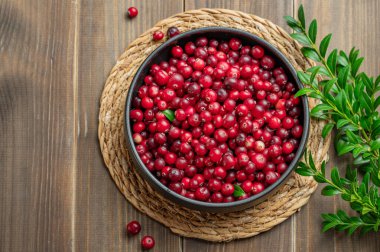 Koyu bir kasede yeşil dallı, ahşap bir arka planda taze yaban mersini. Kırsal tarzda sağlıklı yaban mersini kavramı. Üst görünüm, alanı kopyala.