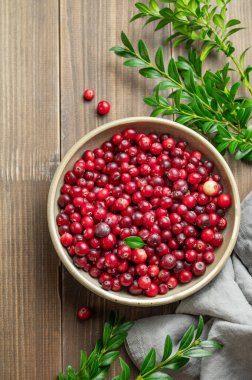 Koyu bir kasede, yeşil dallı ve peçeteli taze kızılcıklar. Kırsal tarzda sağlıklı yaban mersini kavramı. Üst görünüm, alanı kopyala.