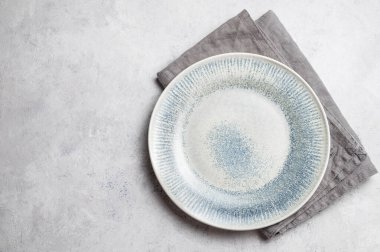 Açık dokulu arka planda keten peçeteyle seramik mavi bir tabak. Konsept bir minimalist yemek atmosferi, mutfak gösterileri veya sunumlar için mükemmel. Üst görünüm, alanı kopyala.