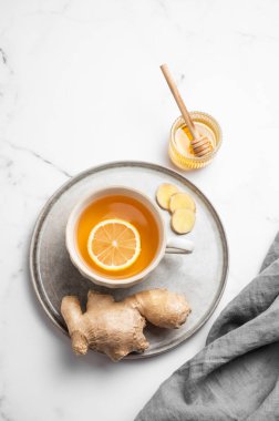 Bir fincan sıcak çay, taze limon ve zencefilli ve bal ve peçeteyle mermer bir tabakta. Dokunulmazlığı ve sağlığı arttırmak için doğal içecek kavramı. Üst görünüm, alanı kopyala.