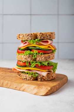 Jambonlu, peynirli, marullu ve sebzeli üçlü sandviç tabakta tam tahıllı ekmek ve bir bardak su ve taze salata. Kavram, taze ve sağlıklı bir atıştırmalıktır. Ön görünüm.