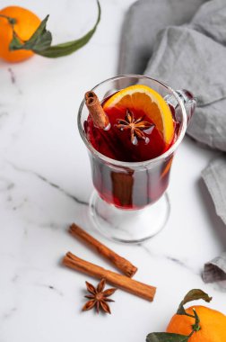 Bir bardak sıcak şarap, portakal, tarçın ve arkaplanda baharat, mandalina ve peçeteli yıldız anason. Sıcak bir kış içeceği ve sıcak bir ev atmosferi. Üst görünüm, alanı kopyala.
