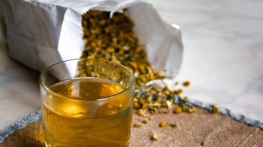 Papatya çayı, dokuma peçetedeki bir bardakta..