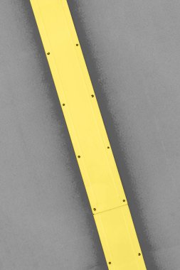 Gri arka planda sarı metal şerit. Çapraz konumlandırılmış. 