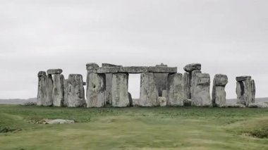 Yeşil çimlerle çevrili antik taş çember anıtı.