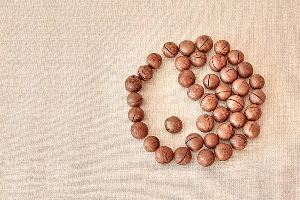 The male and female Yin-Yang symbol is made of macadamia nuts on a light brown background