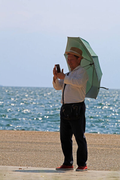 Thessaloniki, Greece  August 9, 2015: A Chinese man standing on a sea street in Thessaloniki