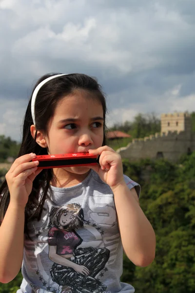 Douce petite fille jouant harmonica bouche — Photo