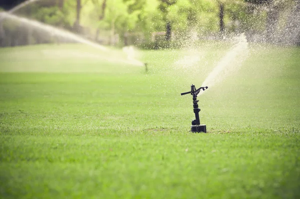 Irrigação por aspersão de água do campo de relva verde — Fotografia de Stock