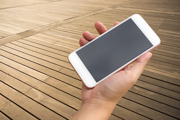 Ręcznie przy użyciu smartfona na podłoże drewniane podłogi. — Zdjęcie stockowe