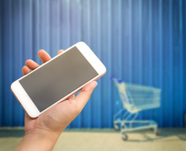 Alışveriş sepeti ile smartphone tutan el 