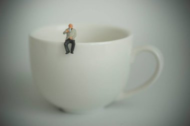 Yaşlı işadamı bir fincanda oturup kahve içiyor.