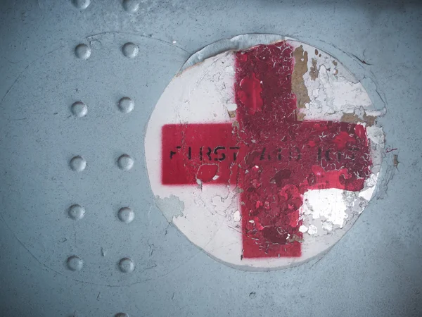Red cross sign on old metal plate