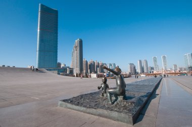 Erkek ve kız Xinghai Meydanı önünde heykel