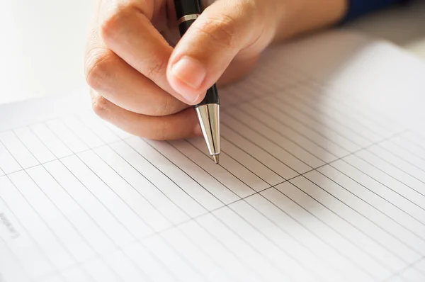 Kvinnliga händer med pennan skriver på papper — Stockfoto