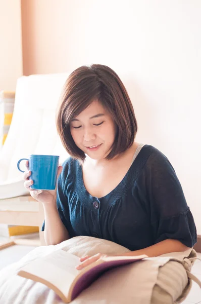 Ung asiatisk kvinna läser bok och dricker kaffe — Stockfoto