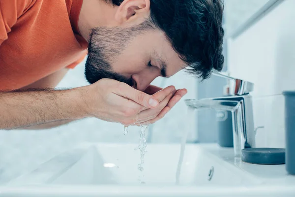 黒い髪の白人男性の肖像水を実行している顔を洗浄しながら彼の目を閉じて — ストック写真