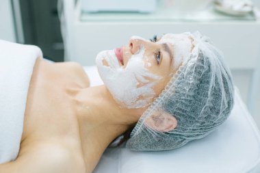 Yüzünde yumuşak beyaz oksijen maskesi varken banyoda yatan ve gülümseyen kadın.