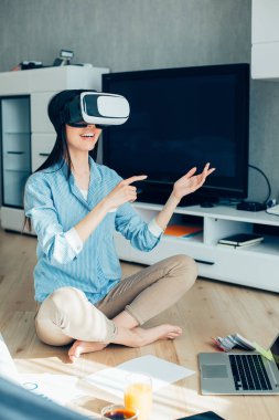 Yerde oturup sanal gerçeklik gözlükleriyle gülümseyen mutlu güzel bayan.