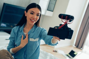 Gülümseyen genç bayan kameraya bakıyor ve evinde kendi videosunu çekiyor.